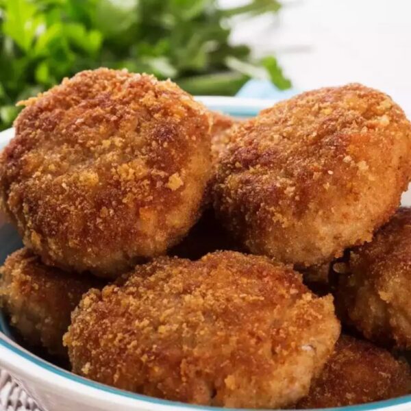 Crispy golden-brown prawn cutlet on a plate, garnished with fresh herbs, served with a side of dipping sauce